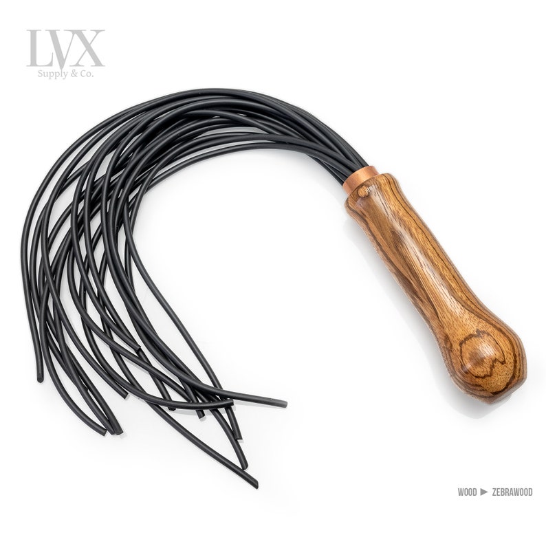 May include: A black leather whip with a wooden handle. The handle is made of zebrawood and has a copper accent. The whip has multiple strands of leather.