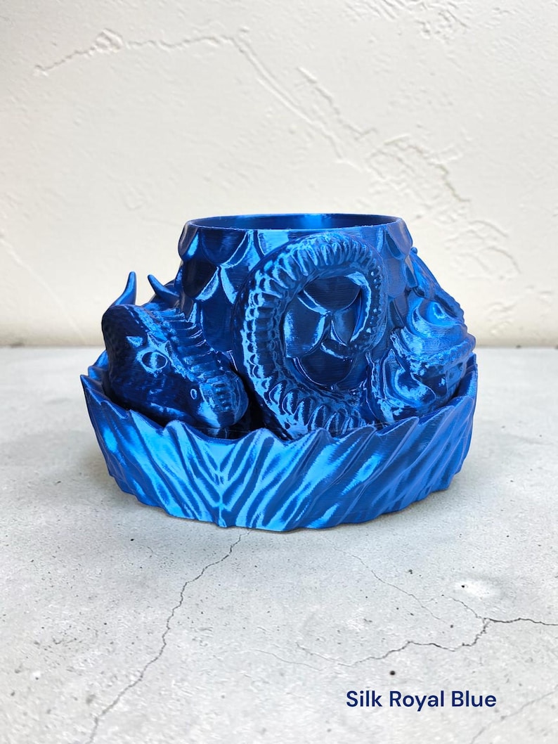 Pode incluir: Um vaso azul royal impresso em 3D com um design de drag&atilde;o. O vaso apresenta uma cabe&ccedil;a e um corpo de drag&atilde;o detalhados, com escamas texturizadas e uma base decorativa. O texto "Silk Royal Blue" est&aacute; na parte inferior.