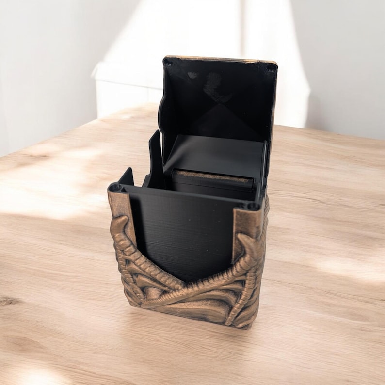 May include: A black and gold card deck box with a dragon design. The lid is open and the box is empty.