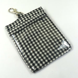 May include: Black and white gingham fabric ID badge holder with a clear plastic window and a silver metal clip.