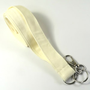 May include: A white fabric lanyard with a silver swivel clasp and a silver key ring.