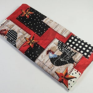May include: Rectangular fabric item with a patchwork design. The pattern includes red, black, and white sections with stars, polka dots, and rooster illustrations. The edges are red.