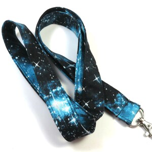 May include: A blue and black galaxy print lanyard with a silver metal clip.