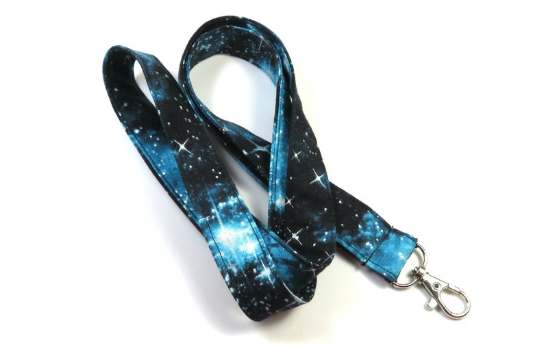 May include: A blue and black galaxy print lanyard with a silver metal clip.