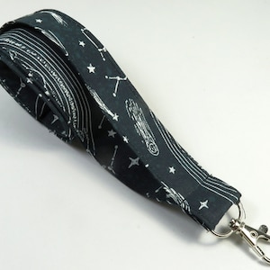 May include: A black lanyard with a white constellation pattern and a silver swivel clip.