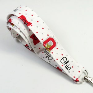 May include: White lanyard with red and grey polka dots, a red and grey Ohio State University logo, and the word "Ohio" in black. The lanyard has a silver metal clip.