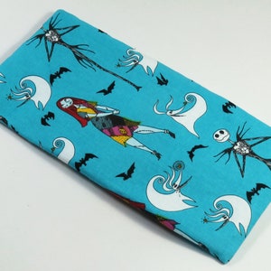May include: A turquoise fabric with a repeating pattern of characters from The Nightmare Before Christmas. The characters include Jack Skellington, Sally, and Zero the ghost dog.
