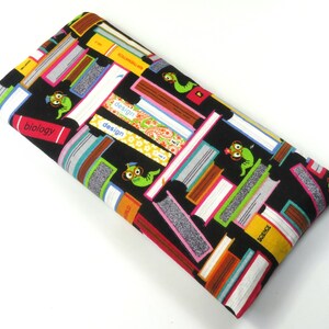May include: Black fabric eye mask with a colorful print of stacked books and cartoon worms wearing glasses. The books have titles like "biology", "design", and "science".