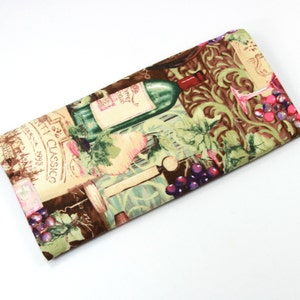 May include: A fabric wine bottle bag with a green, brown, and white design featuring a wine bottle, grapes, and the text "Vini Classico 1993".