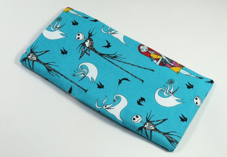 May include: A turquoise fabric with a repeating pattern of Jack Skellington and Sally from The Nightmare Before Christmas. The fabric is ideal for crafting projects such as cushions, bags, and quilts.