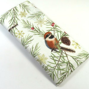 May include: A white fabric eye mask with a wintery design featuring a small brown and blue bird perched on a pine branch with red berries and gold snowflakes.