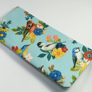 May include: A light blue fabric pouch with a repeating pattern of colorful birds and flowers. The birds are blue, yellow, red, and white. The flowers are yellow, red, blue, and white.