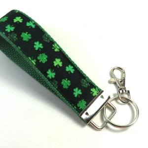May include: A green and black key chain with a shamrock pattern and a silver key ring.