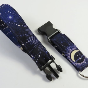 May include: A black and blue lanyard with a constellation print and a black plastic clip. The lanyard has a silver key ring attached to it.