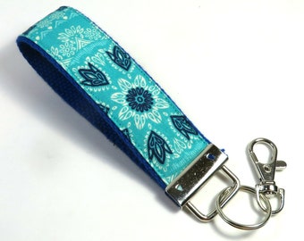 May include: A teal blue and navy blue patterned key chain with a silver key ring and a silver clip.