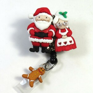 May include: A red and white Santa Claus and Mrs. Claus Christmas themed retractable badge holder with a gingerbread man charm.