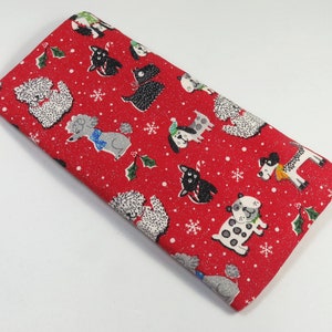 Puede incluir: Tela roja con un patrón repetido de perros con gorros y bufandas de Papá Noel. Los perros están en varias poses y razas, incluyendo caniches, terriers y sabuesos. La tela está cubierta de una fina brillantina blanca.