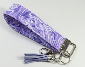 May include: Purple and white marbled fabric key chain with a silver key ring and a purple tassel.