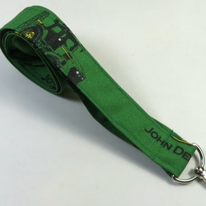 Puede incluir: Lanyard verde con un diseño de tractor John Deere y un clip giratorio plateado.