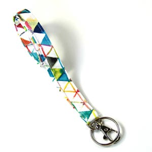 May include: A white fabric key chain with a colorful geometric pattern and a silver swivel clip.