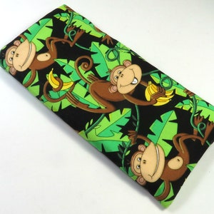 May include: A black fabric pouch with a repeating pattern of monkeys holding bananas and green leaves. The monkeys are brown with white eyes and smiling.