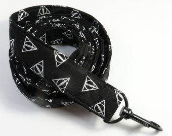 May include: Black and silver dog leash with a repeating pattern of the Deathly Hallows symbol. The leash has a black metal clip.
