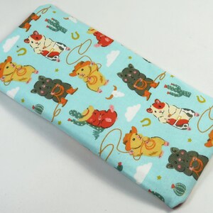May include: A light blue fabric with a repeating pattern of cartoon hamsters wearing cowboy hats and riding horses. The hamsters are brown, orange, and white. The fabric has a white background with clouds and stars.