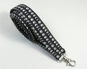 May include: Black fabric lanyard with a white moon phase pattern and a silver metal clip.