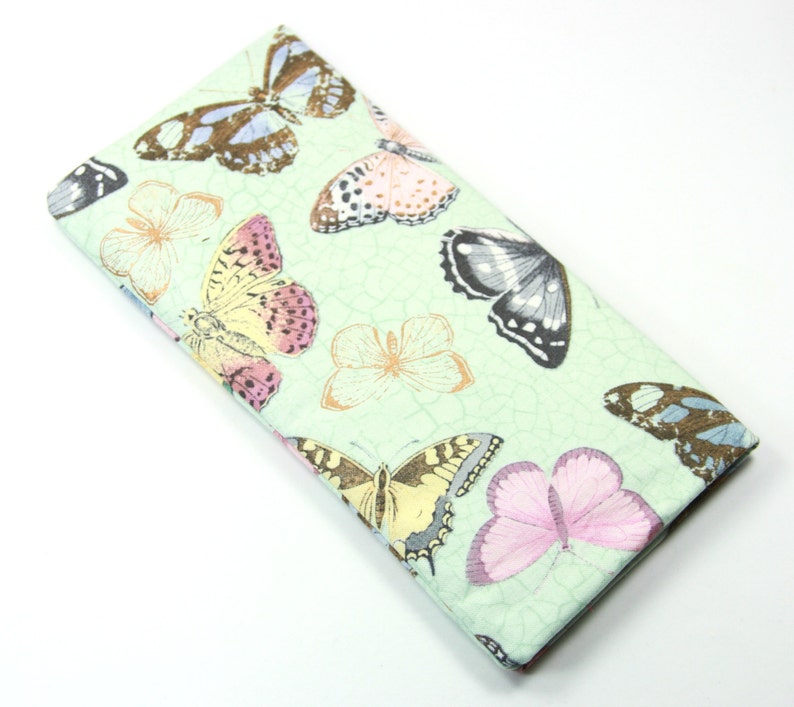 May include: A light green fabric case with a repeating pattern of colorful butterflies. The case is made of a soft, textured fabric.