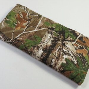 May include: A rectangular brown, green, and white camouflage fabric eye pillow. The pillow is made of soft fabric and is perfect for blocking out light and promoting relaxation.