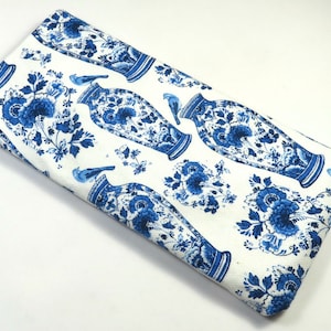 May include: White fabric with a blue and white pattern of vases and flowers. The fabric is folded in half and the pattern is visible on both sides.
