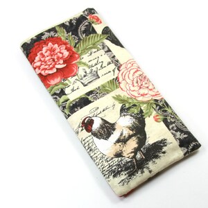 May include: A cream-colored fabric eyeglass case with a black and white rooster design and red and white flowers. The case has a vintage French script pattern.
