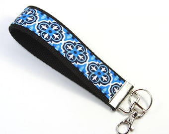 May include: A black and blue patterned key chain with a silver key ring. The pattern features blue and white geometric shapes.