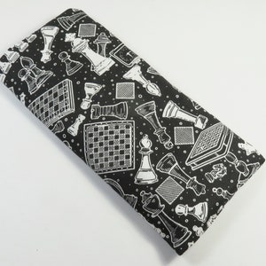 May include: Black fabric with a white chessboard pattern. The fabric features a repeating design of chess pieces and chessboards.