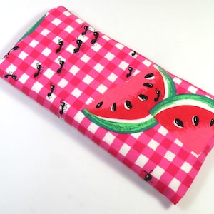 May include: A pink and white gingham fabric with black ants and watermelon slices. The fabric is perfect for crafting projects like bags, pillows, and quilts.