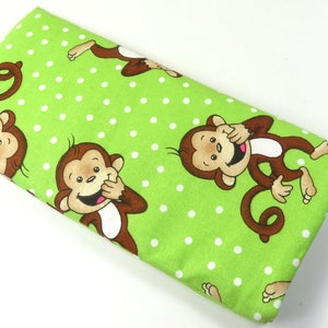 May include: Green fabric with a white polka dot pattern and a repeating design of brown monkeys covering their mouths and laughing.