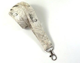 May include: A white lanyard with a black and white map print. The lanyard has a silver swivel clasp.
