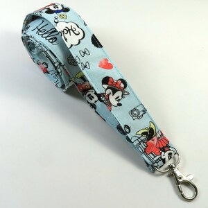 May include: A light blue lanyard with a Mickey Mouse and Minnie Mouse print. The lanyard has a silver metal clip. The lanyard has the text "Hello" and a speech bubble with the text "Hope" on it.