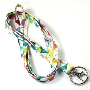 May include: A colorful lanyard with a geometric pattern in shades of blue, green, yellow, pink, and red. The lanyard has a silver swivel clip.