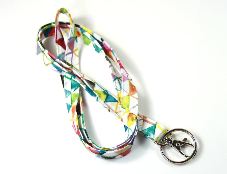 May include: A colorful lanyard with a geometric pattern in shades of blue, green, yellow, pink, and red. The lanyard has a silver swivel clip.