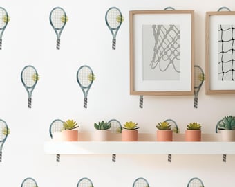 May include: White wall with a repeating pattern of blue and green tennis rackets with yellow tennis balls. Two framed pictures of tennis nets are on the wall above a white shelf with potted succulents.