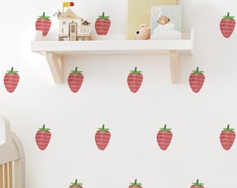 May include: A white wall decorated with watercolor strawberry decals. A white shelf holds a wooden toy house, books, and a small stuffed animal. The strawberries are red with green tops, creating a playful, fruity theme.