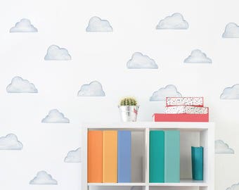 May include: A white wall with blue watercolor cloud decals. A white bookshelf with orange, yellow, blue, and green books. A small potted cactus sits on the top shelf.