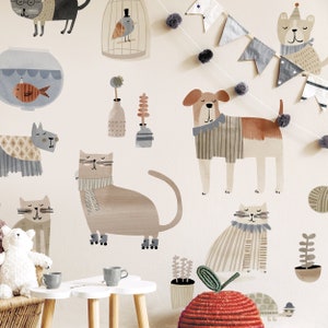 May include: A set of colorful animal wall decals featuring cats and dogs wearing scarves and hats. The decals are on a light beige wall with a string of gray and white flags and pom-poms.