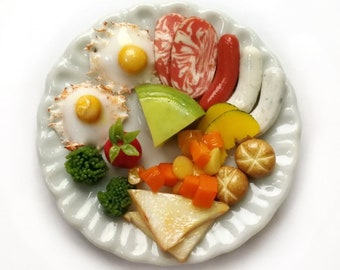 May include: A white plate with a miniature breakfast meal, including fried eggs, sausage, melon, and vegetables.