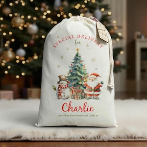 May include: A cream Christmas sack with a drawstring. It features a festive illustration of a snowman, Christmas tree, and Santa Claus. Text on the sack reads "SPECIAL DELIVERY for Charlie" and "Lots of love from Mummy and Daddy xx".