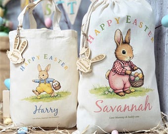 May include: Two off-white Easter-themed tote bags and drawstring bag. Each bag features a cartoon bunny carrying a basket of eggs, the words "Happy Easter", and a name. Wooden bunny-shaped tags hang from the bags.