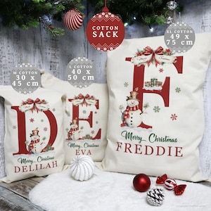May include: Off-white cotton Christmas sacks with red lettering and snowman illustrations. Sizes include M (11.8 x 17.7 inches), L (15.7 x 19.7 inches), and XL (19.3 x 29.5 inches). Each sack features a name, such as Delilah, Eva, or Freddie.