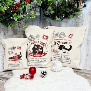 May include: Three cream-colored Christmas gift bags with cat illustrations and festive text. One bag reads "Meowy Christmas" with a black cat. Another says "Overnight Delivery for Charlie." The third bag says "Special Delivery for Daisy."
