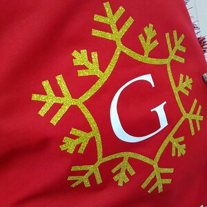 May include: Red fabric stocking with a gold glitter snowflake and the letter "G" in white.